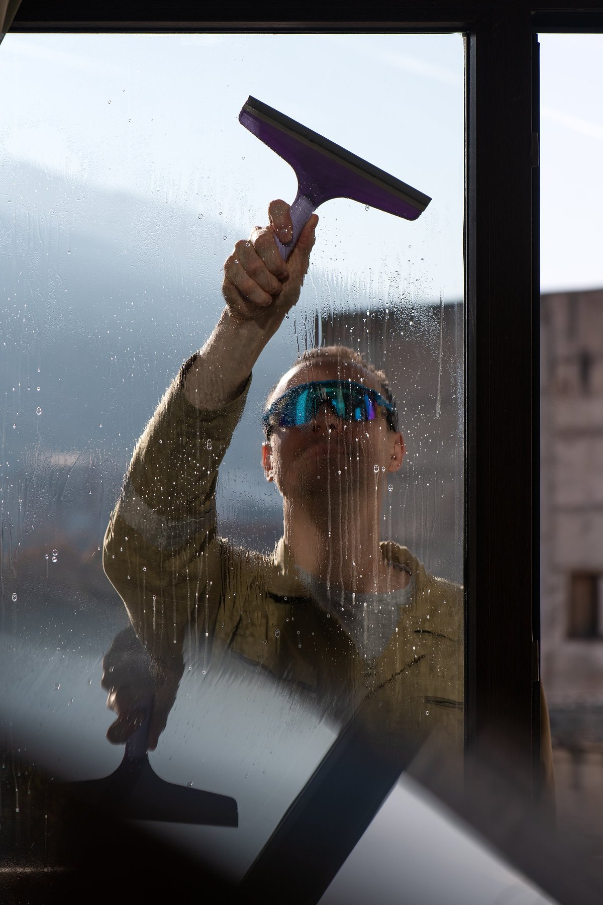 Male professional window cleaner working with squeegee tool